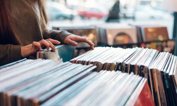 Close up of a woman hands choosing vinyl record in music record shop. Music addict concept. Old school classic concept. Focus on the hands and a vinyl record.