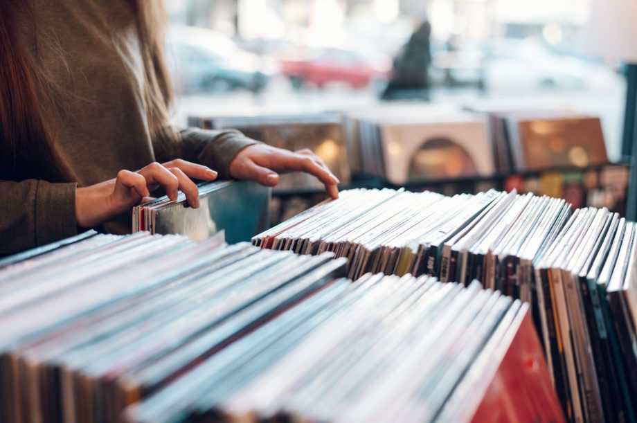 Close up of a woman hands choosing vinyl record in music record shop. Music addict concept. Old school classic concept. Focus on the hands and a vinyl record.